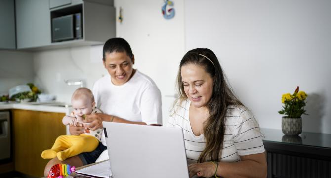 same sex couple navigating computer and baby