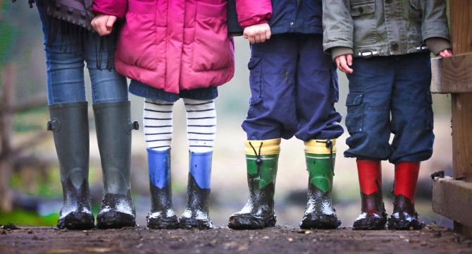 Images of four pairs of rainboots standing in the mud